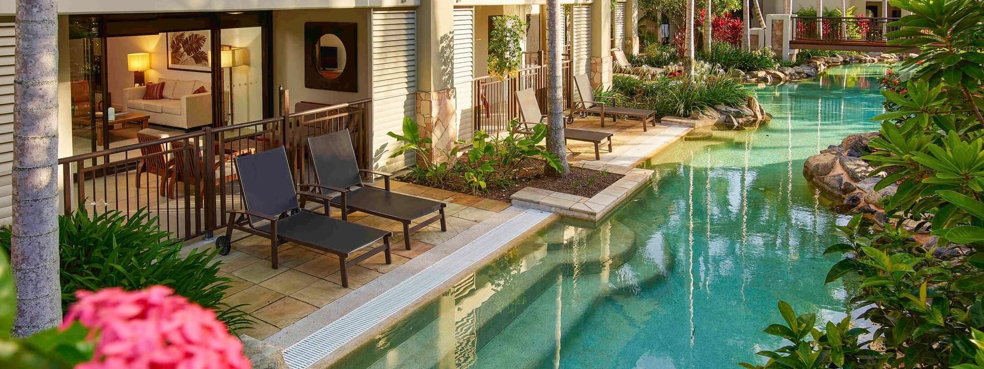 Swim-Out Apartments with pool, lounge chairs and surrounded by lush vegetation at Pullman Port Douglas