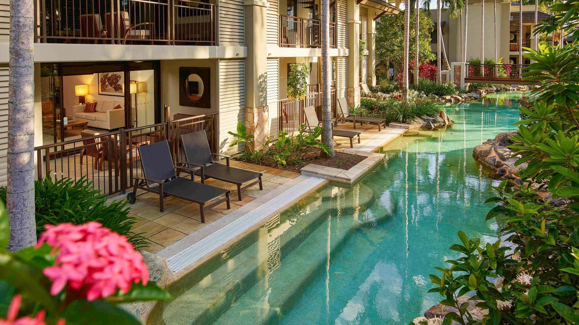 Swim-Out Apartments with pool, lounge chairs and surrounded by lush vegetation at Pullman Port Douglas