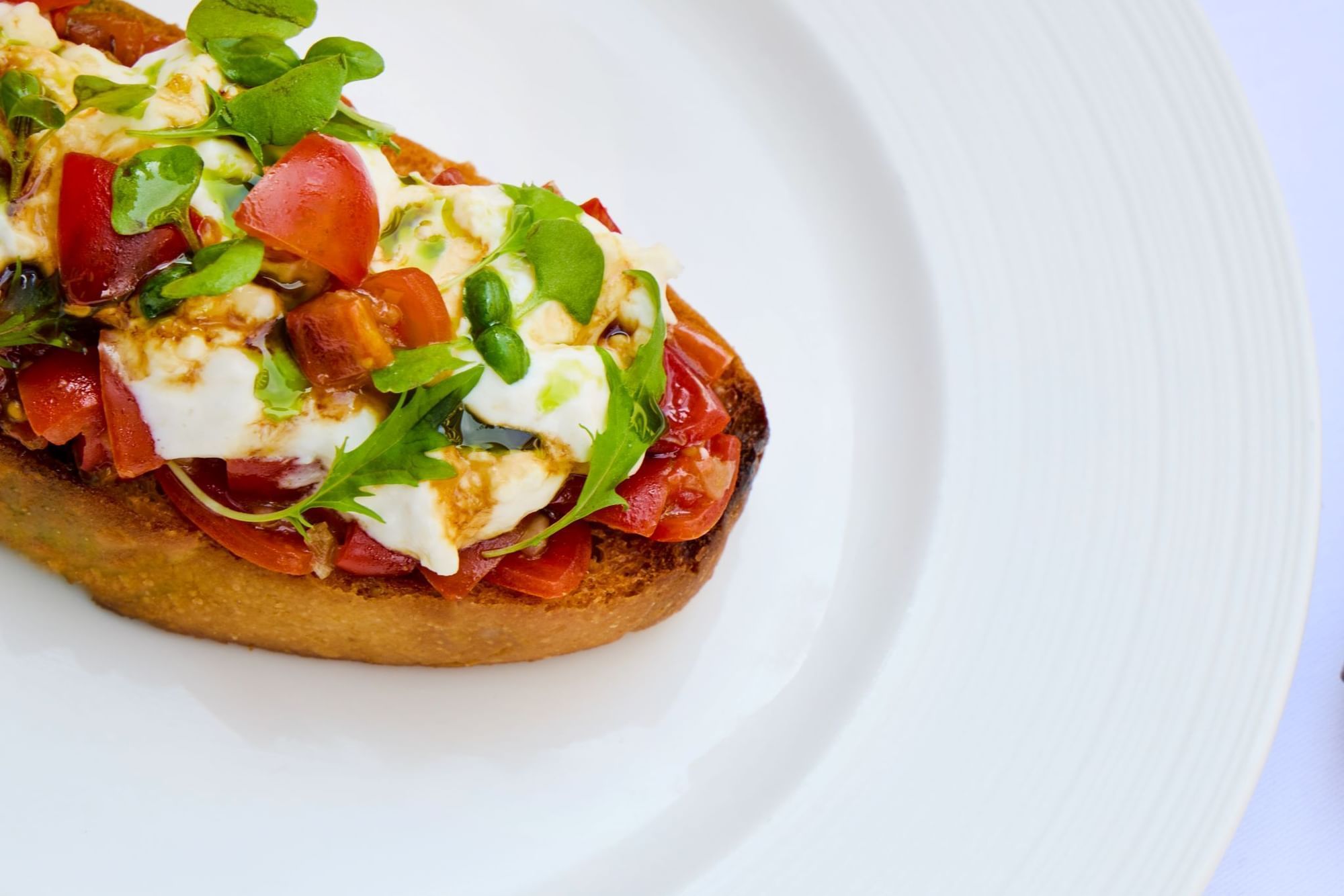 Delicious bruschetta topped with fresh tomatoes, mozzarella, and herbs served in Whitcomb's Terrace at The Londoner Hotel