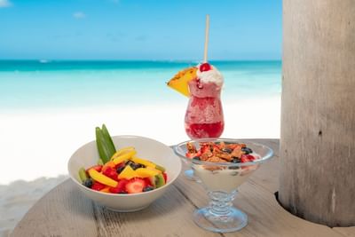 Fruit salad with fresh juice served on beachside dining table at Passions on the Beach