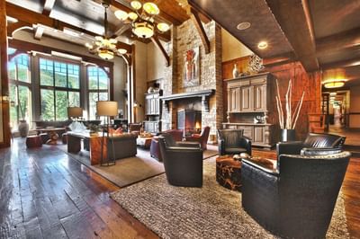 Cozy lodge-style living room featuring a stone fireplace by the large windows at Hotel Park City Autograph Collection
