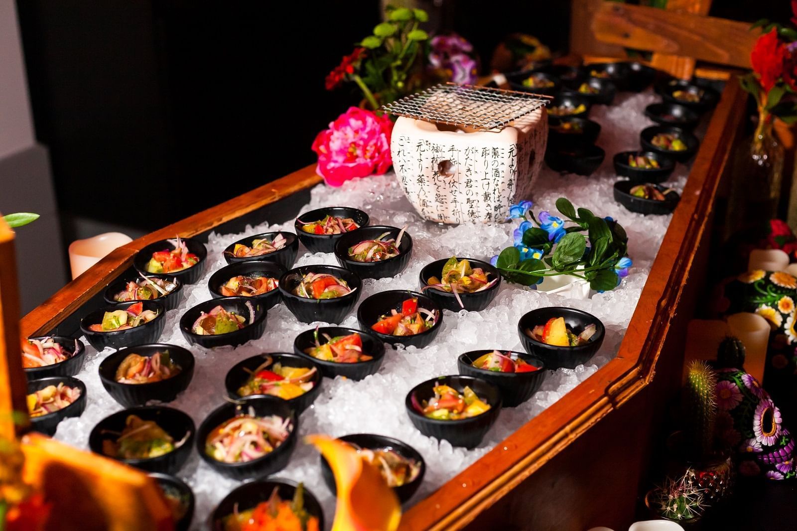 Display of small black bowls filled with colorful seafood salads on a bed of ice at The Kitchens