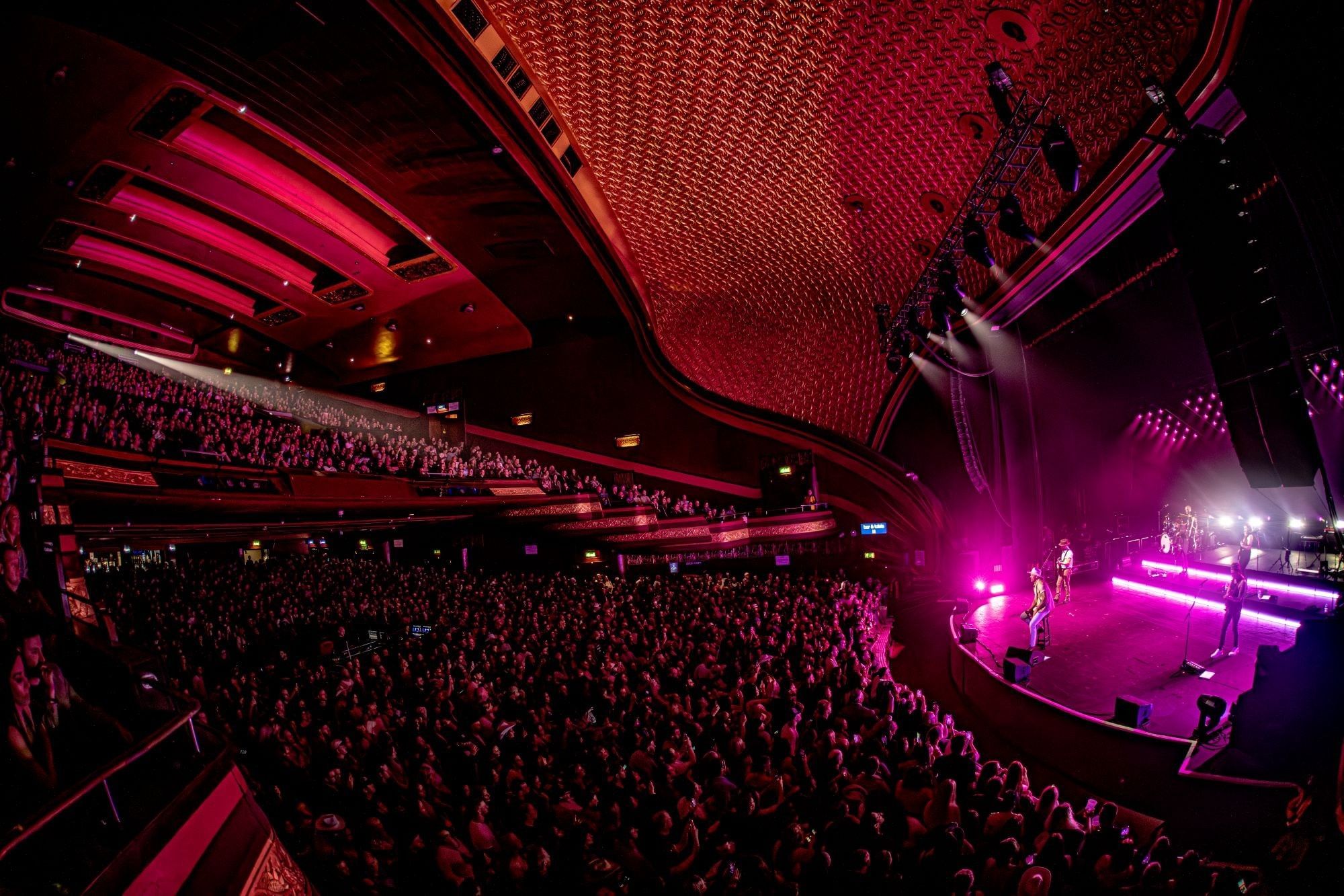 Crowded audience watching a live band performance on a stage.
