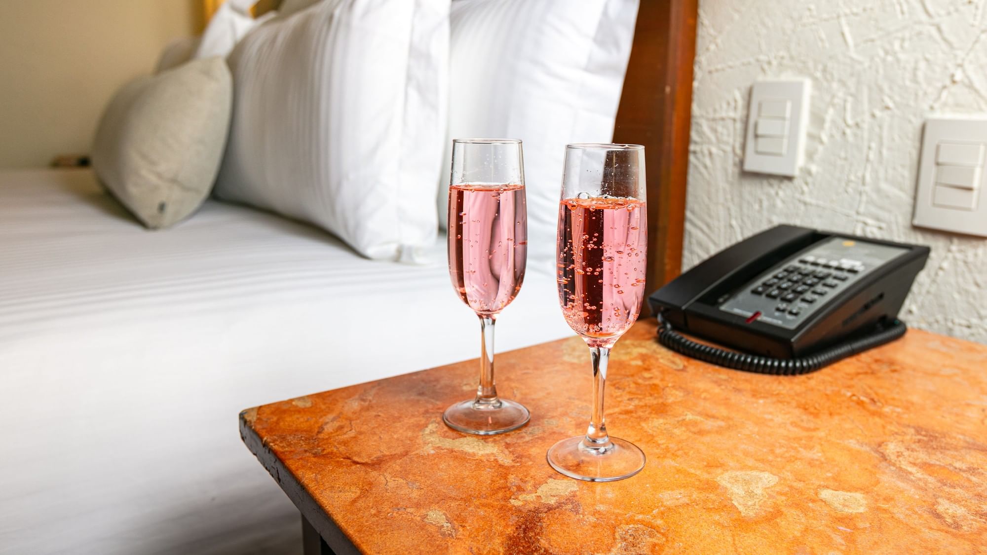 Two glasses of champagne on a table with a phone at Camino Real Guadalajara in Zapopan