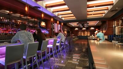 Patrons sitting at the lit bar counter with high chairs in Harborside Bar and Lounge at Harborside Inn Boston