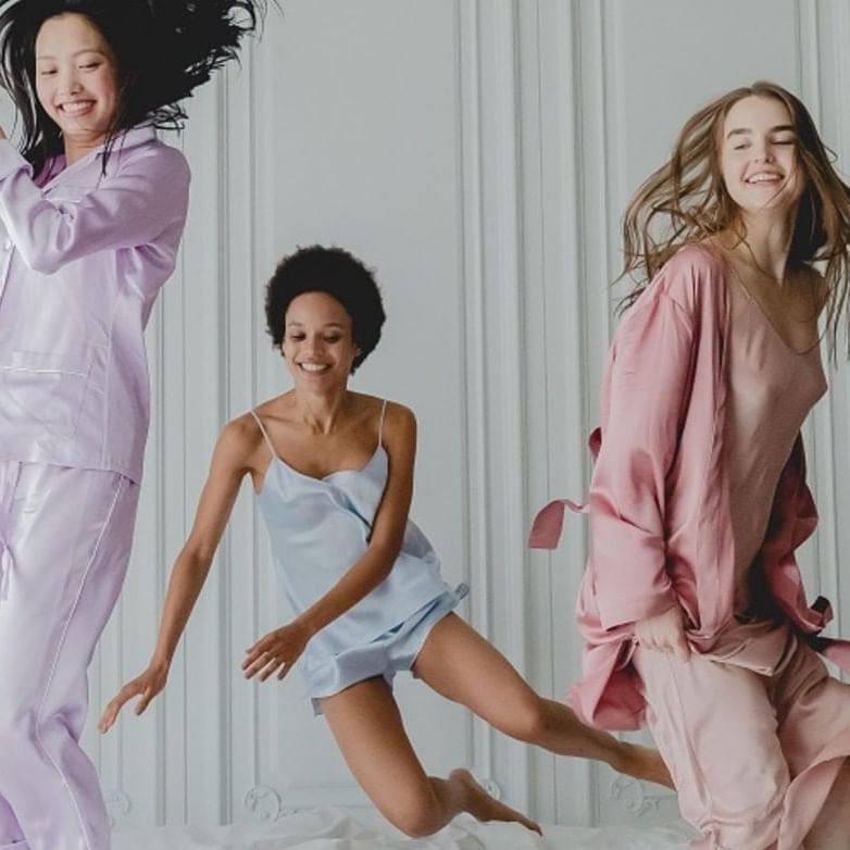 Three girls in colorful pajamas leaping on a bed at Sofitel Brisbane Central