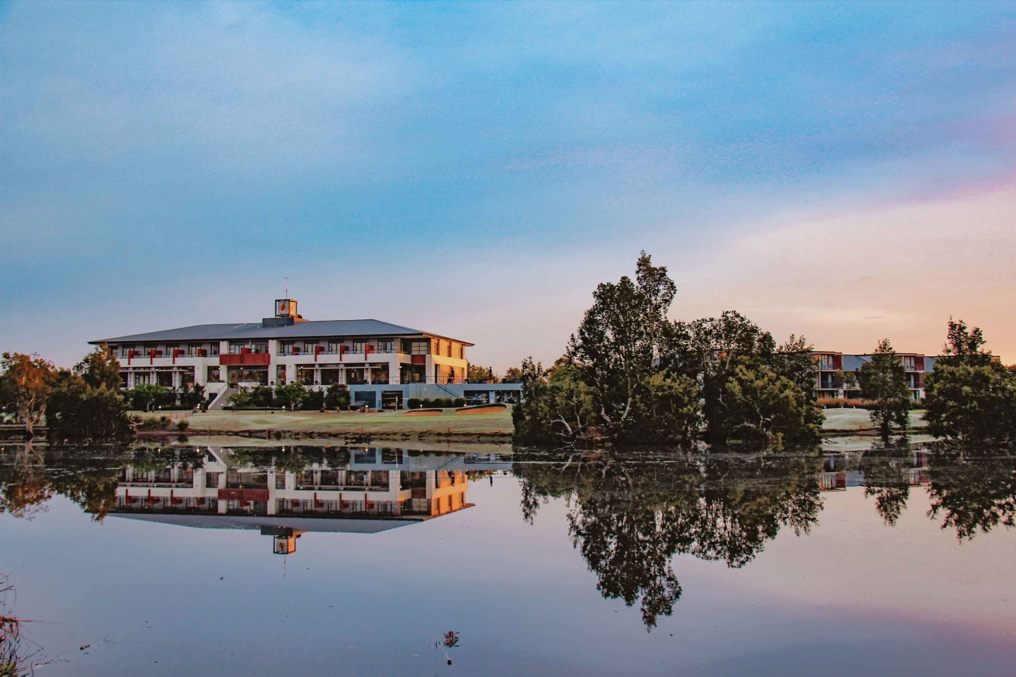Mercure Kooindah Waters reflecting on a calm lake at dusk under a pastel sky