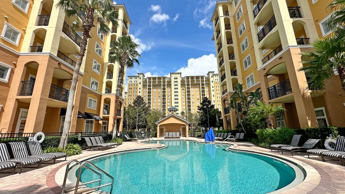 A large pool with lounge chairs and buildings in the background
