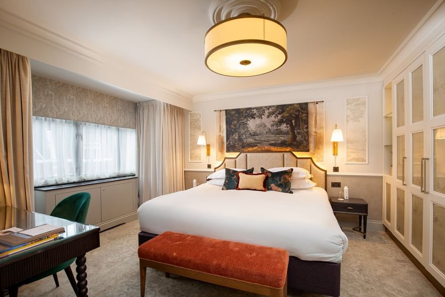 Bed with side tables and a working desk near window in Suite at The Capital Hotel, Apartments and Townhouse
