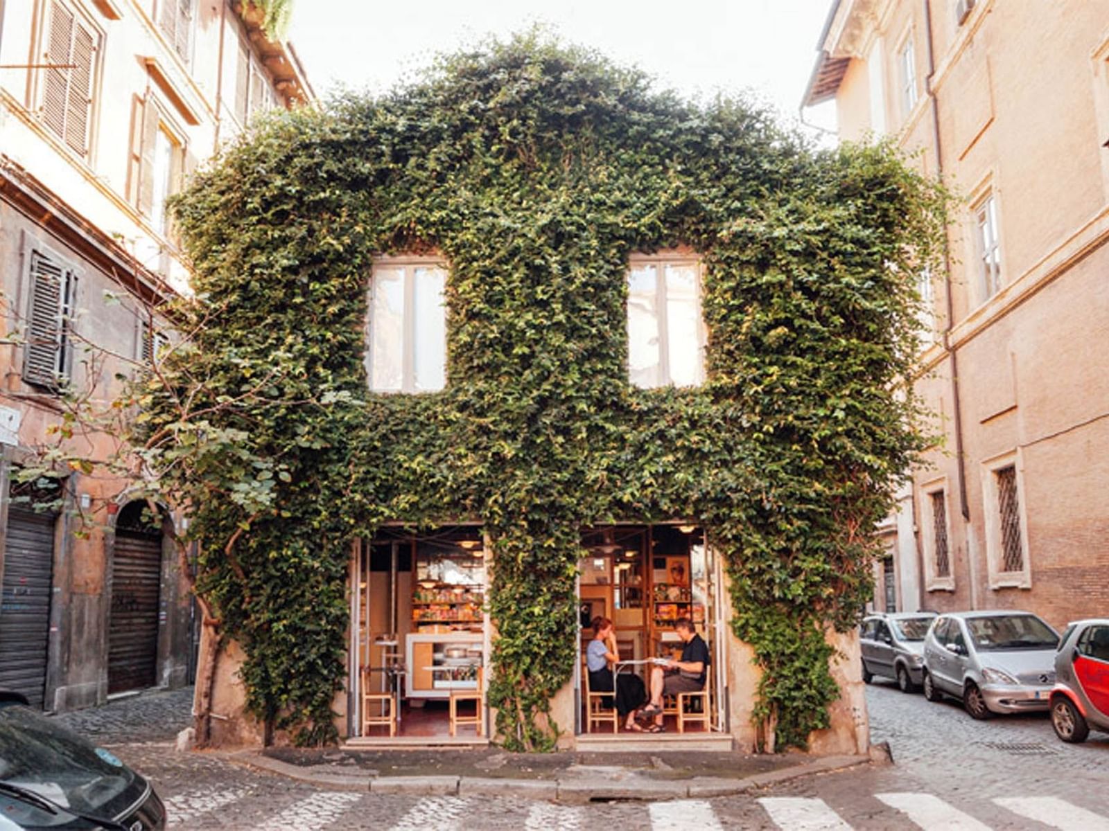 Ivy-covered cafe building with large front windows and people dining outside near The Guardian Hotel