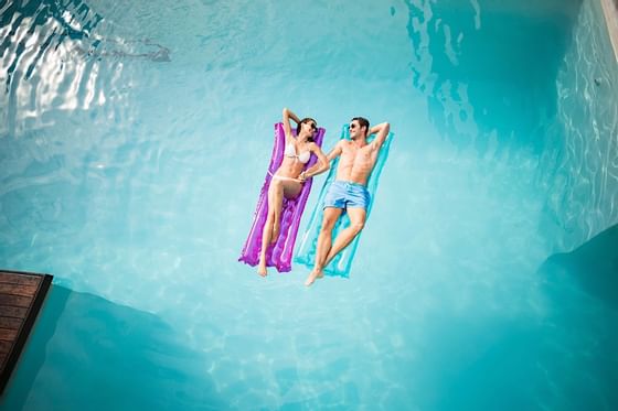 Happy couple floating on pool floats.