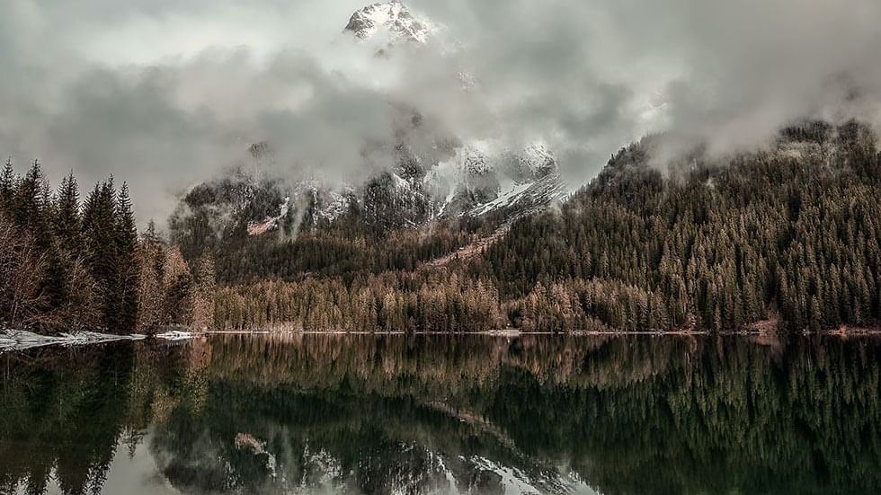 Misty mountains behind a lake near Falkensteiner Hotel Antholz