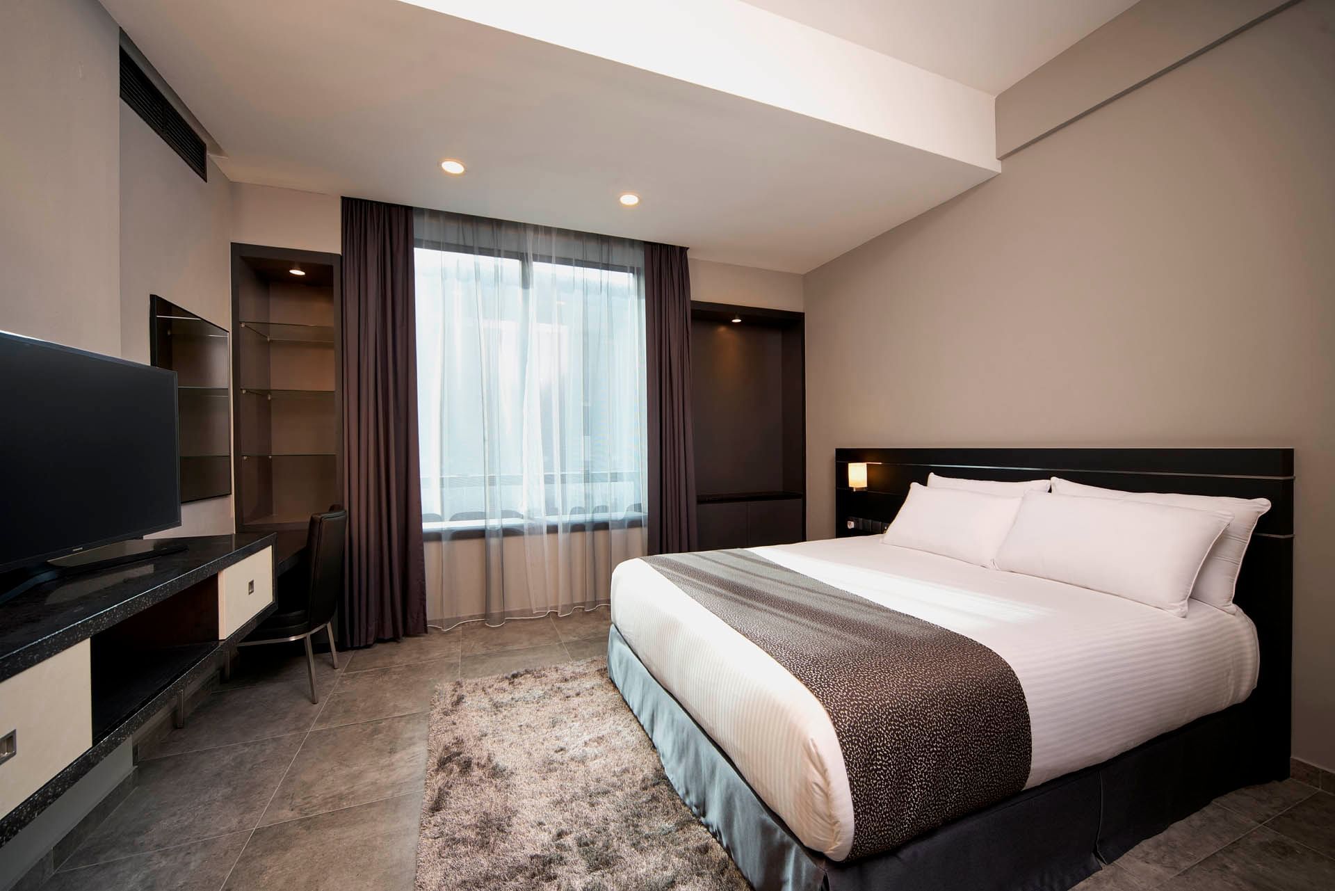 Image 4: Modern One Bedroom Premier with queen bed, sleek decor, TV, and soft natural light at Orchard Grand Court