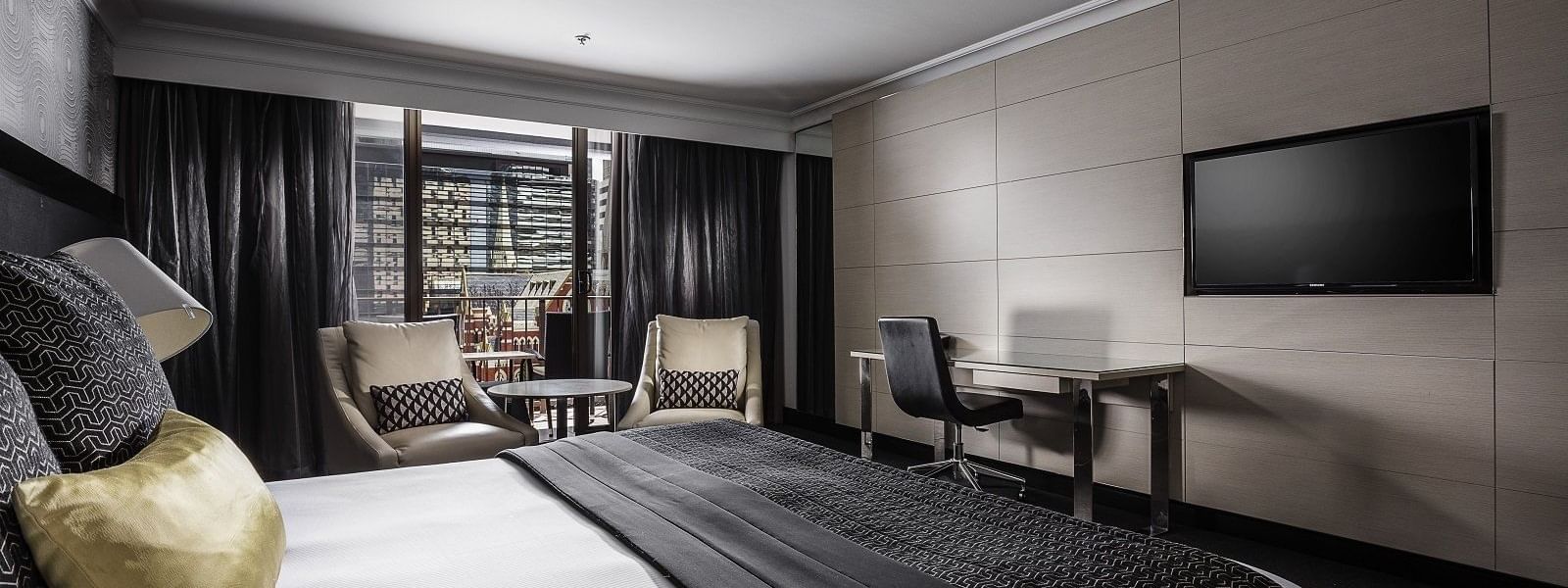 Luxurious Deluxe Balcony Room boasting a plush king bed and seating area at Pullman Brisbane King George Square