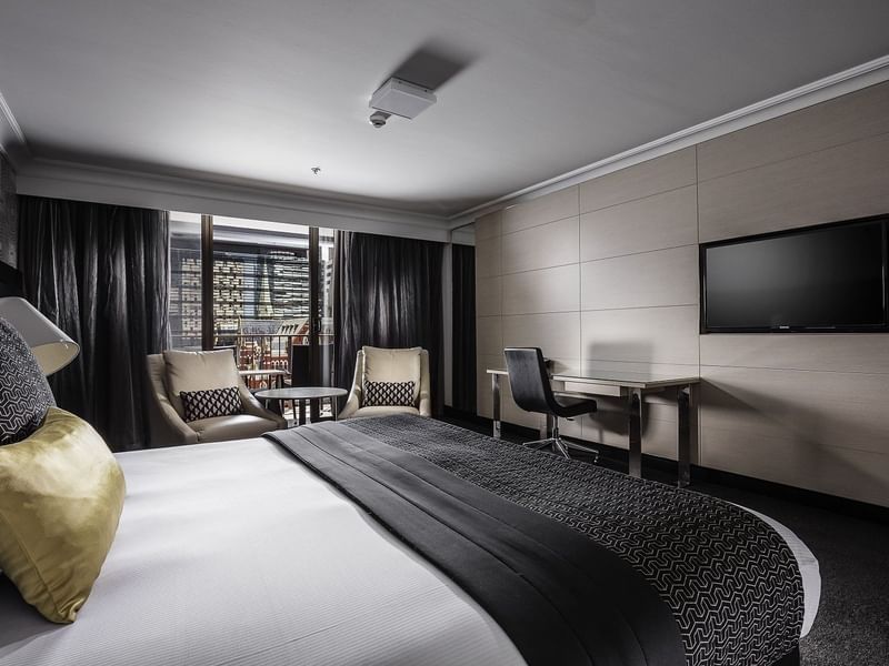 Luxurious Deluxe Balcony Room boasting a plush king bed and seating area at Pullman Brisbane King George Square