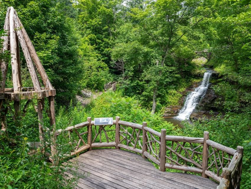 Wooden deck surrounded by lush greenery overlooking Stratton Falls and trail near The Roxbury