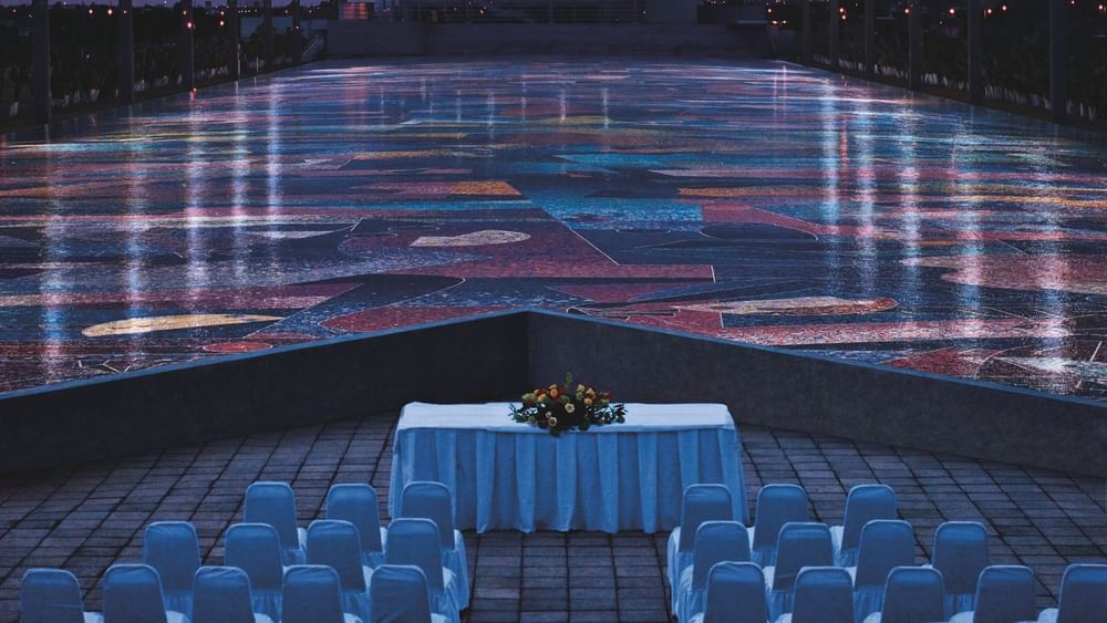 Elegant Parque Cultural Ben Guirón with white chairs facing a stunning, colorful mosaic floor near Camino Real Pachuca