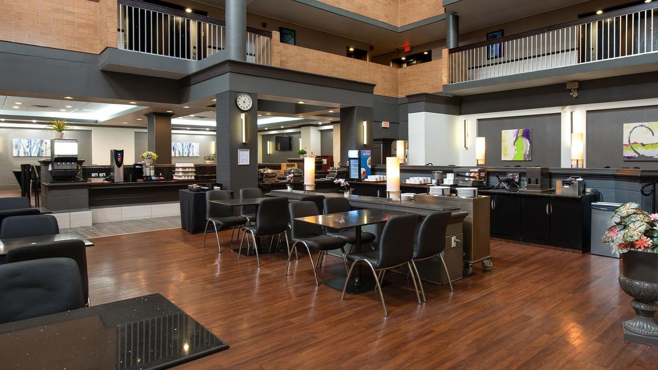 Modern hotel lobby with dark wood floors, black seating, and breakfast buffet area at Coast Calgary University Area Hotel by APA