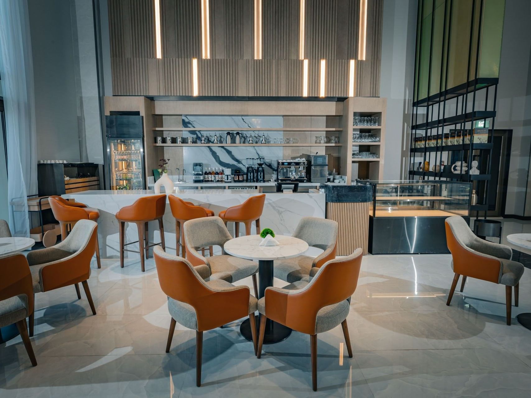 Lounge area with round tables, cushioned chairs, and a marble counter with shelves and a glass display case.