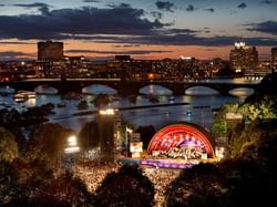 Dusk view of a concert at the Hatch Shell with the Charles River and Longfellow Bridge in the background.