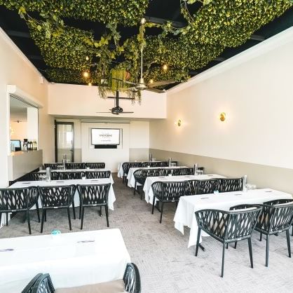 Dining area with tables and chairs under a green plant ceiling at Mercure Charlestown.