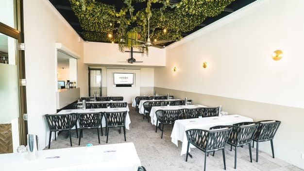 Dining area with tables and chairs under a green plant ceiling at Mercure Charlestown.