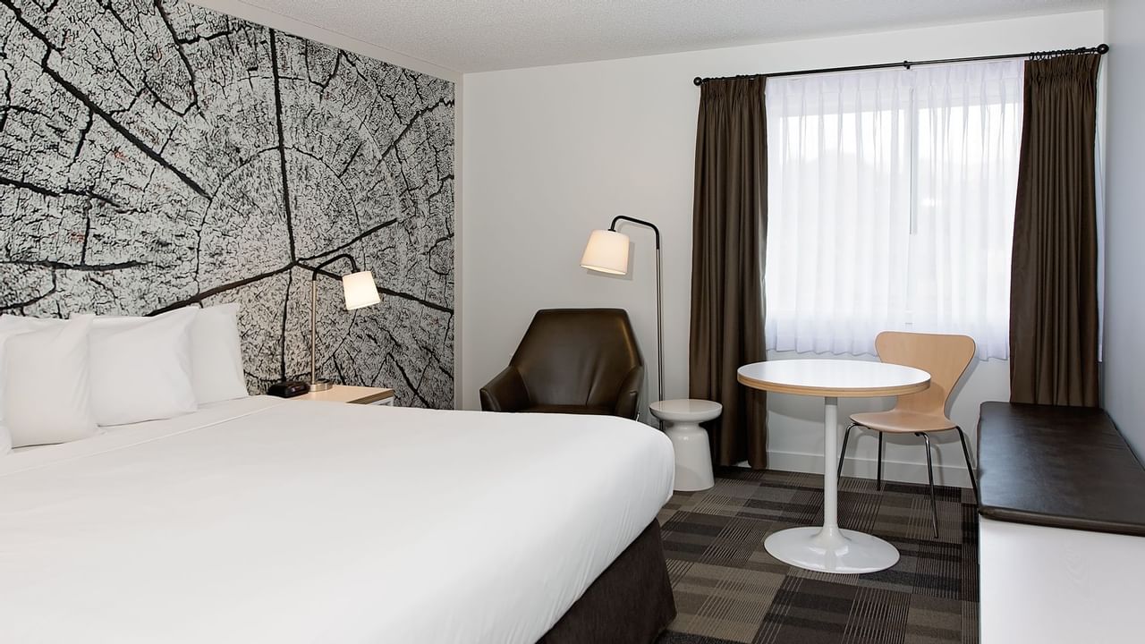 Bed in hotel room with artwork of tree trunk