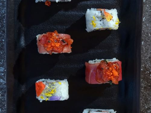 Plato negro para servir con varios rollos de sushi decorativos en La Terraza del Santo de Hacienda del Mar Los Cabos.