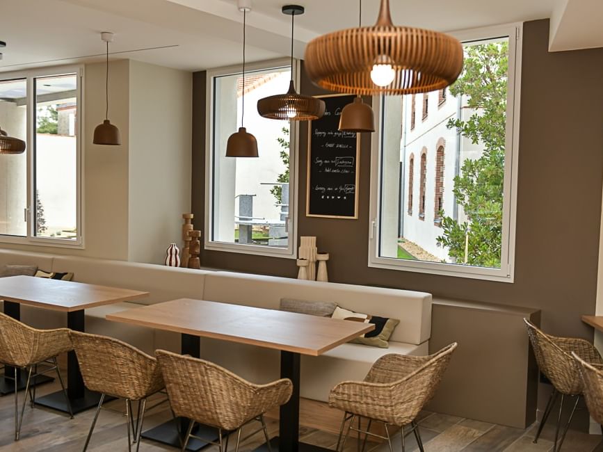 Salle à manger avec tables, chaises et banquette au Hôtel Rivella.