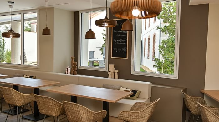 Salle à manger avec tables, chaises et banquette au Hôtel Rivella.