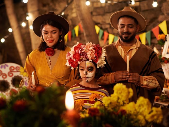 A family at Hacienda del Mar Los Cabos, celebrating Dia de los Muertos with candles, costumes, and a vibrant flower crown