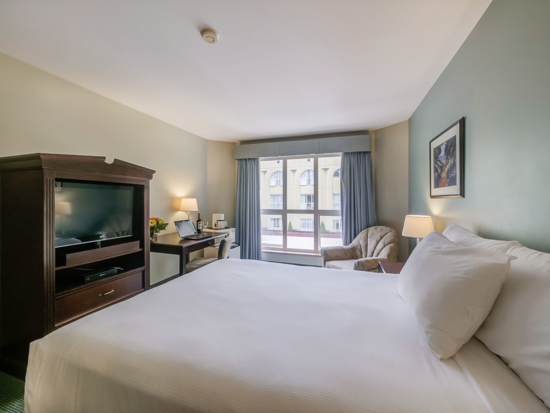 TV & work desk facing bed in Single Queen Bed at Harrison Lake Hotel