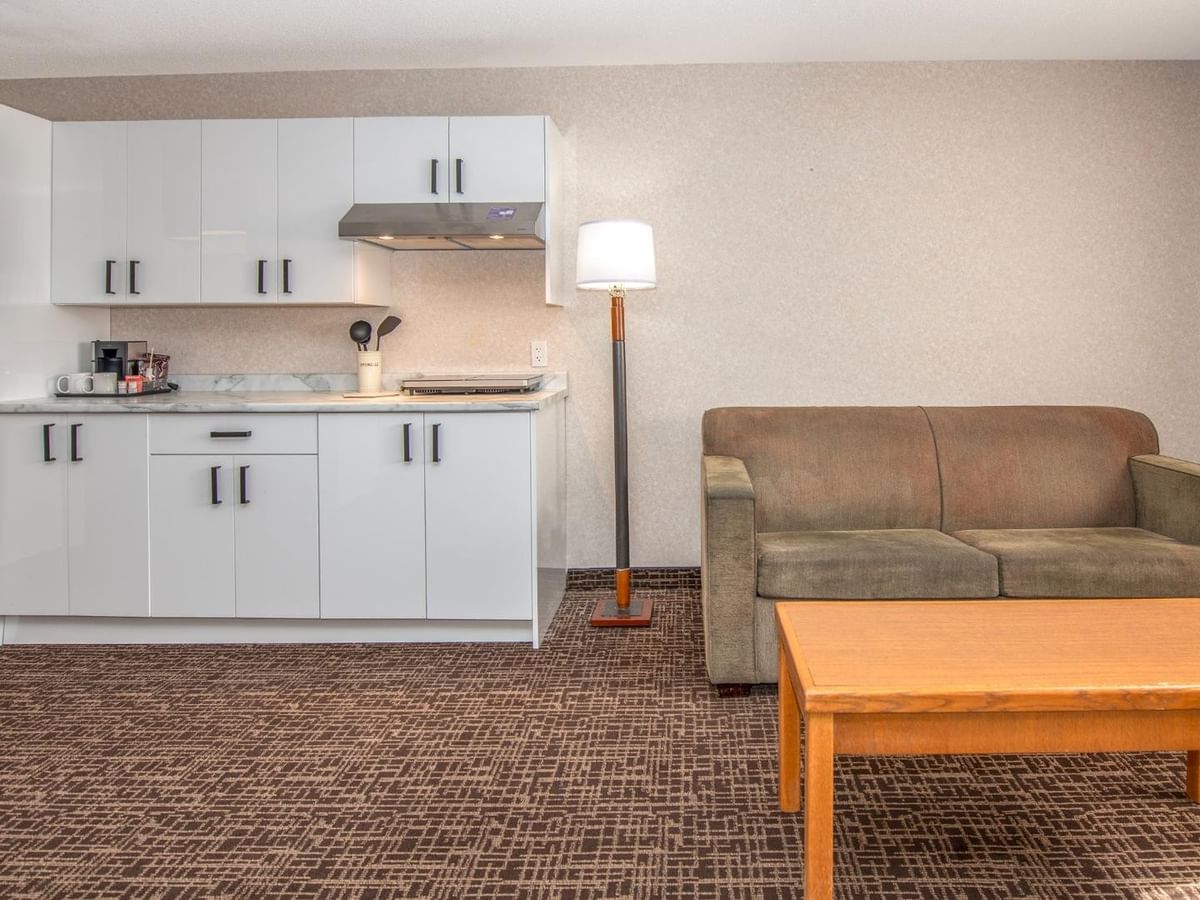 Living room with couch, wooden coffee table, kitchenette, and refrigerator.