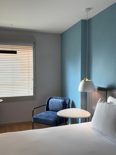 A modern hotel room for a best place to stay in Bogota at Habitel Hotel Select with a large plush bed, and a cozy armchair