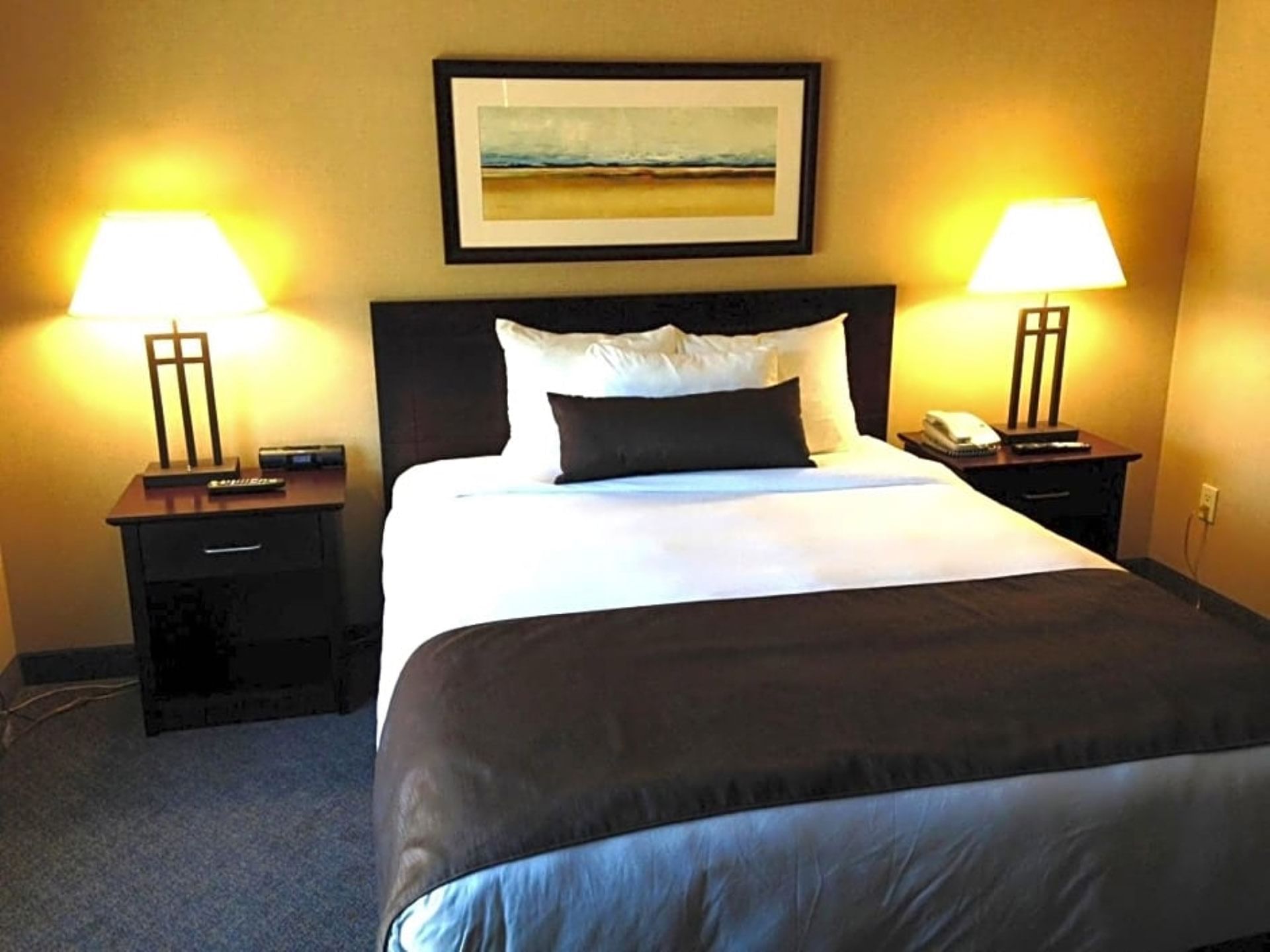 Nightstands with bed lamps by the king bed in Studio One Queen Bed at Franklin Suite Hotel
