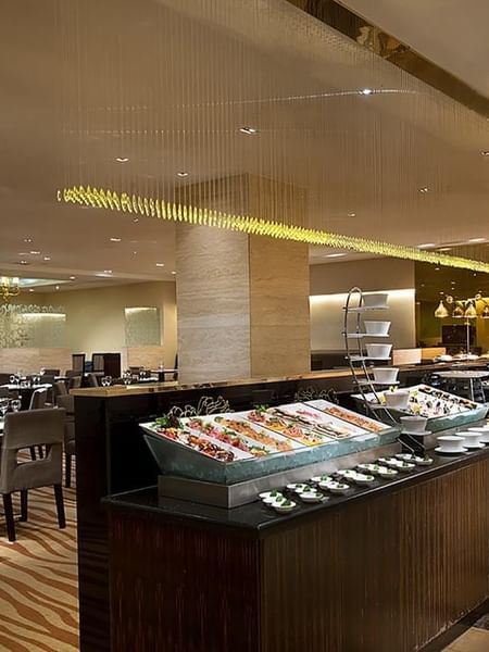 Opened buffet and dining tables arranged in Rainbow Room Coffee Shop at Celebrity International Grand Hotel