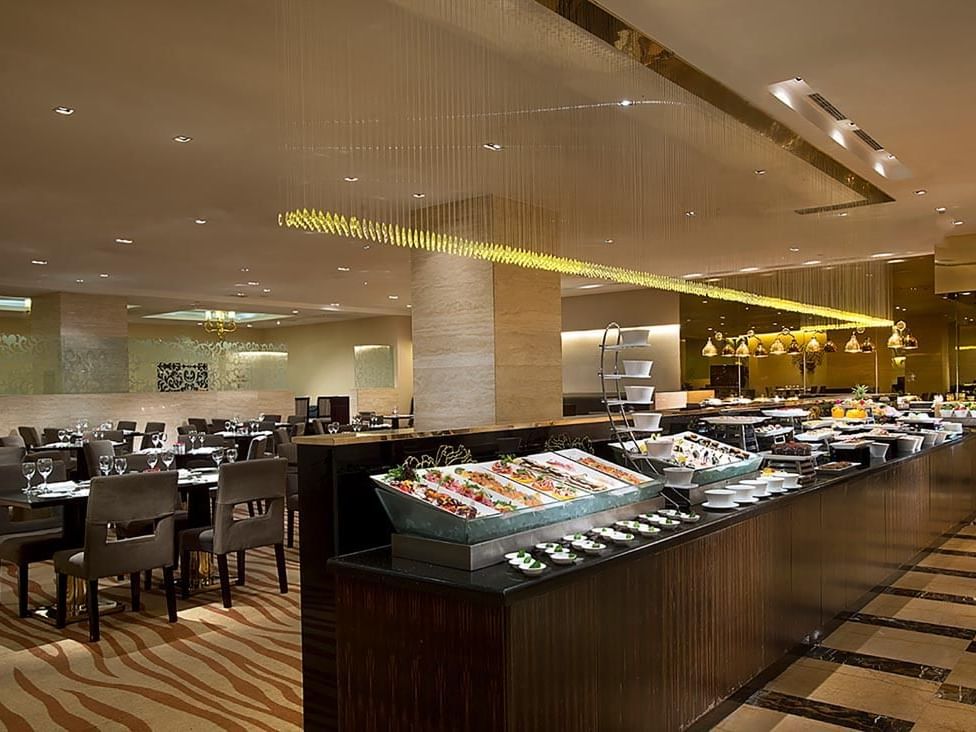 Opened buffet and dining tables arranged in Rainbow Room Coffee Shop at Celebrity International Grand Hotel