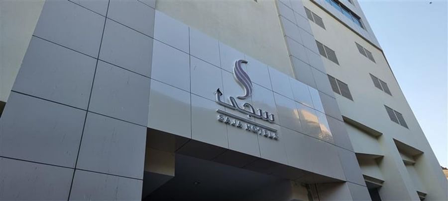 Exterior silver signage for Saja Hotels mounted on a modern grey tiled building facade at Saja by Warwick Makkah