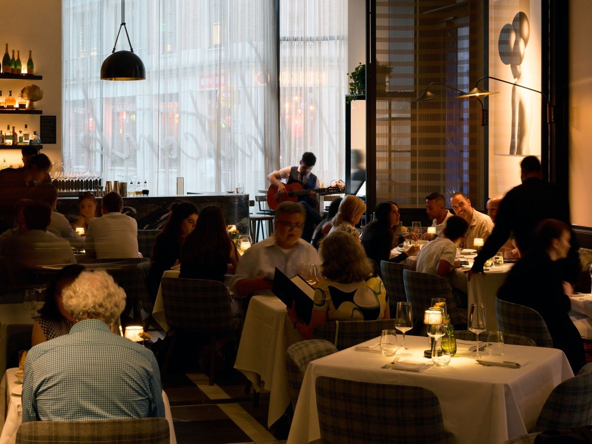 Whitcomb’s restaurant at The Londoner Hotel with guests dining, plush seating, and contemporary décor