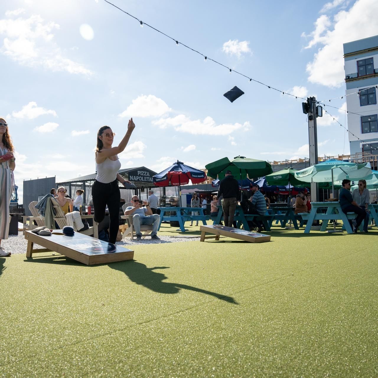 Two ladies playing cornhole on a sunny day in Beer Garden at The Artisan Hotel at Tuscan Village