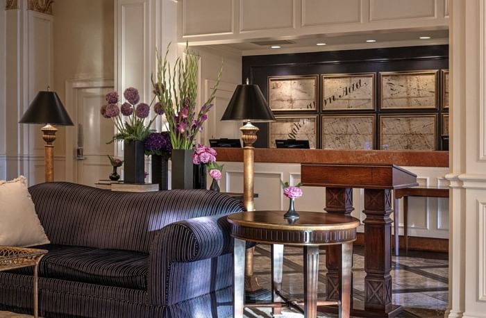 Striped sofa by a round table under gold lamps in the grand lobby at Warwick Melrose Dallas