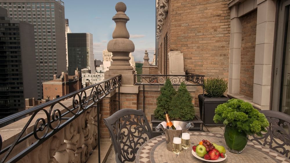 Champagne and fruit on a table by a stone railing under a city skyline at Warwick San Francisco