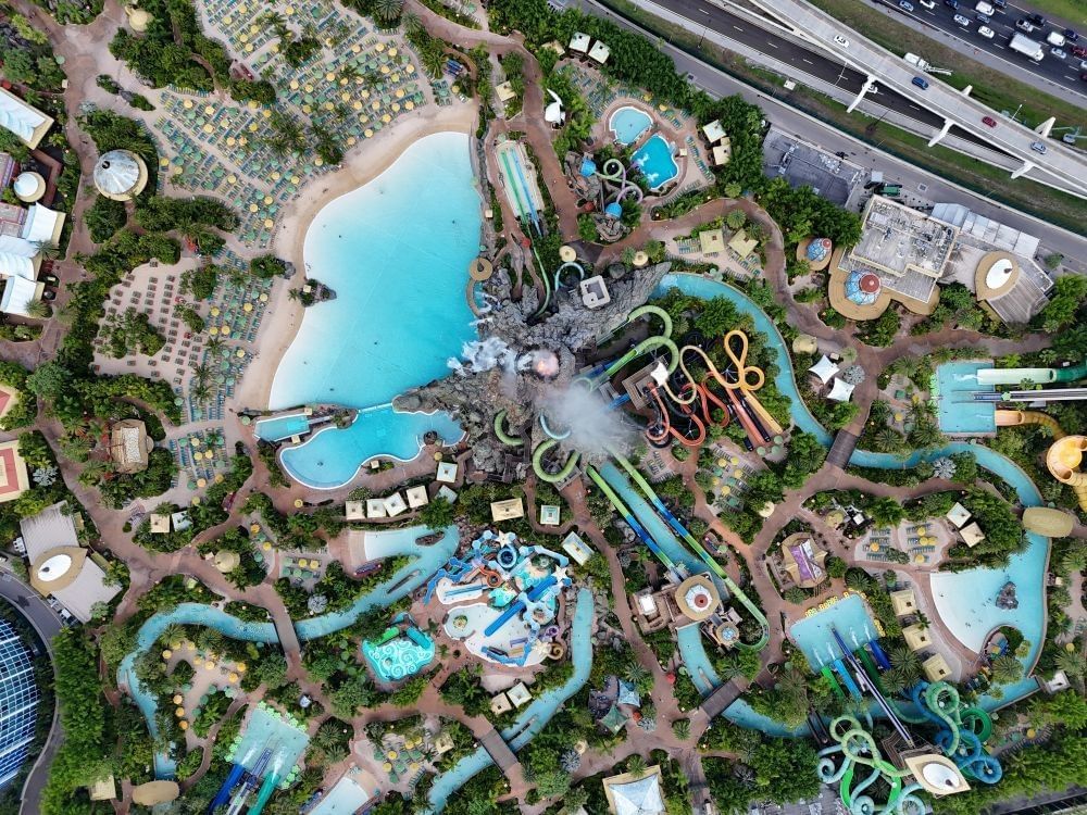 An aerial shot of Volcano Bay water park, with a pool, twisting colorful waterslides, and a large lazy river.