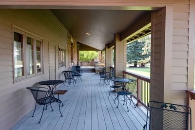 Long outdoor porch with numerous tables and chairs at The Ranch at Ucross overlooking the grounds