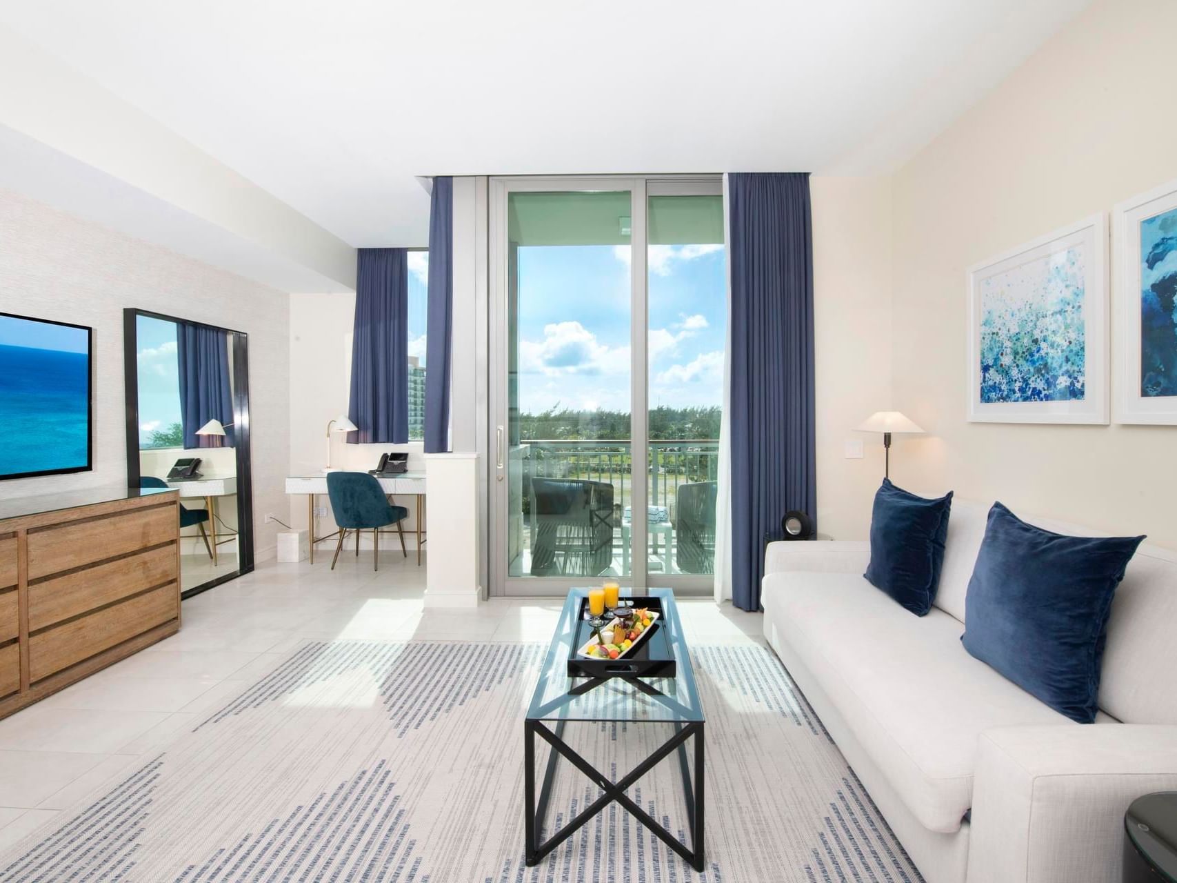 Stylish living area with a comfy sofa, modern desk, & balcony with ocean views in S303 Room at The Residences at Seafire.