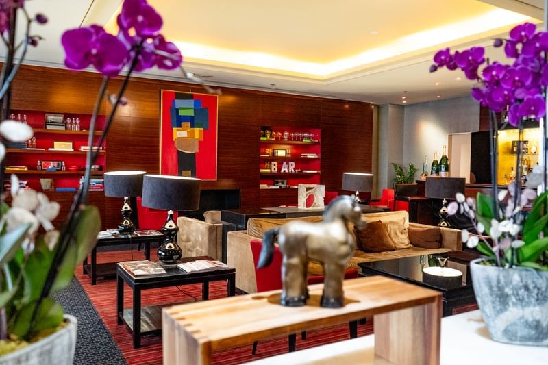Lounge with colorful artwork, cozy seating, ambient lighting, and decorative orchids in Bar Le W at Warwick Paris