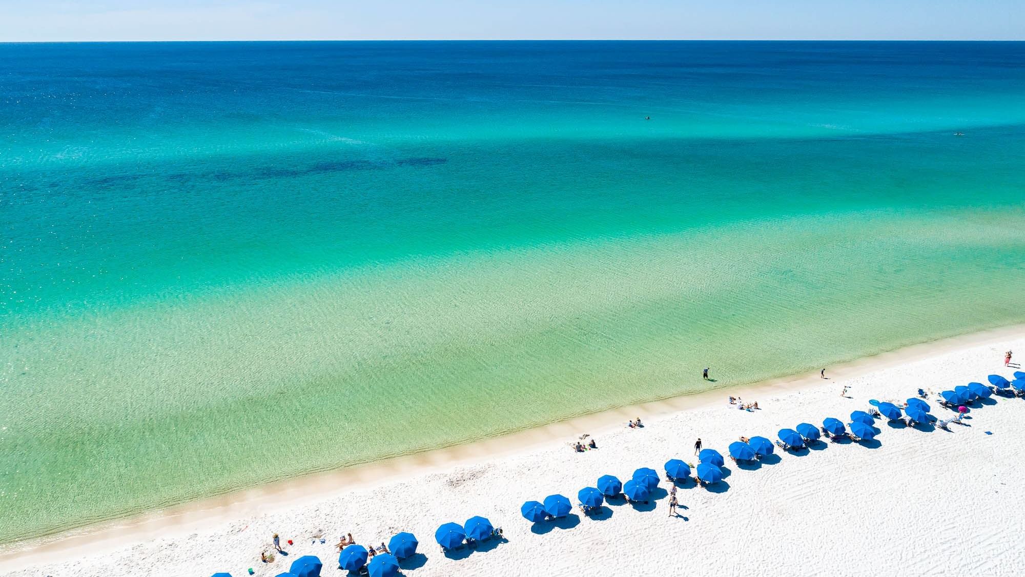 Beach chairs and umbrellas line the Watersound Beach Club private beach shoreline next to Watersound Inn on 30A