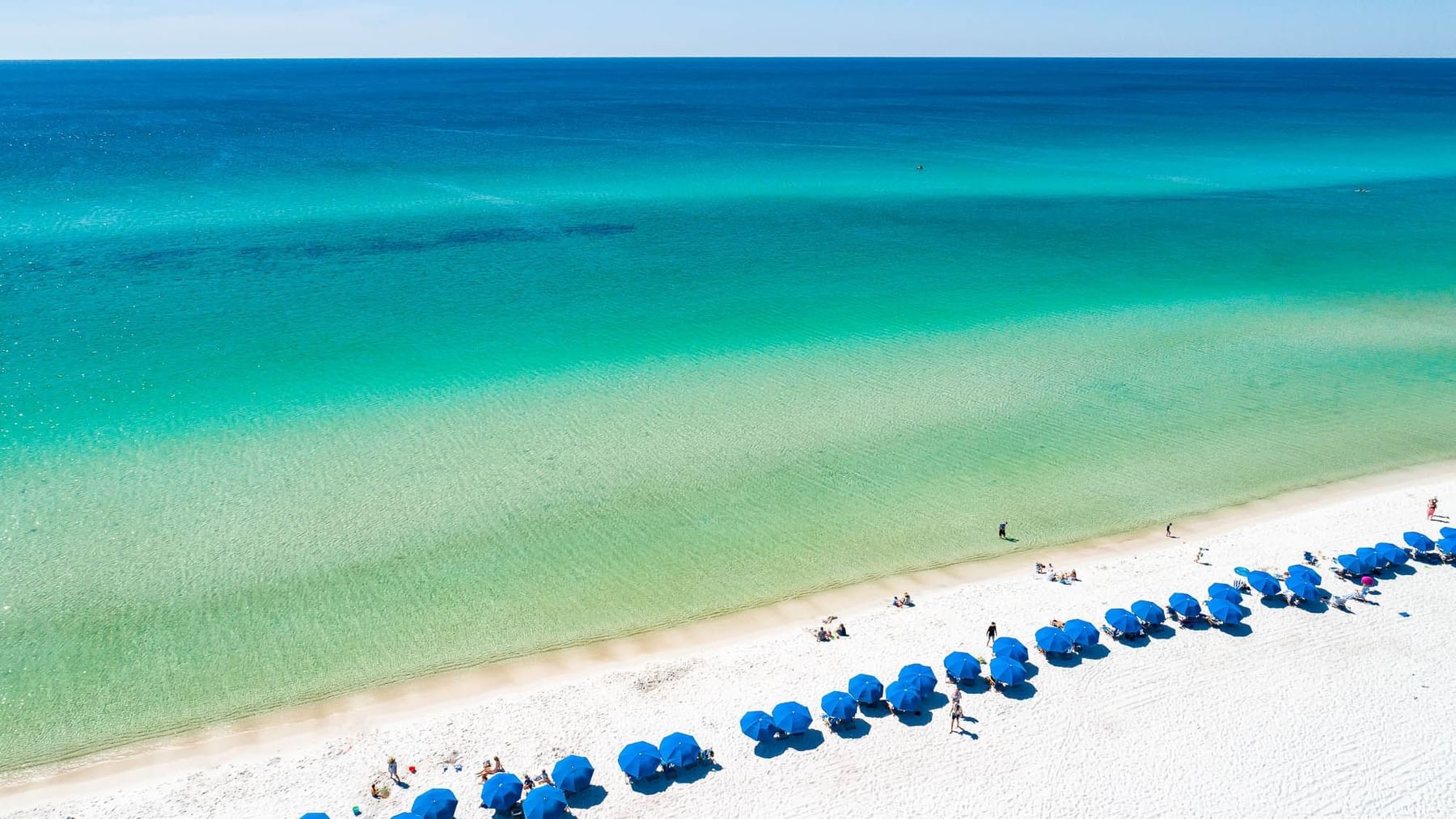 Beach chairs and umbrellas line the Watersound Beach Club private beach shoreline next to Watersound Inn on 30A
