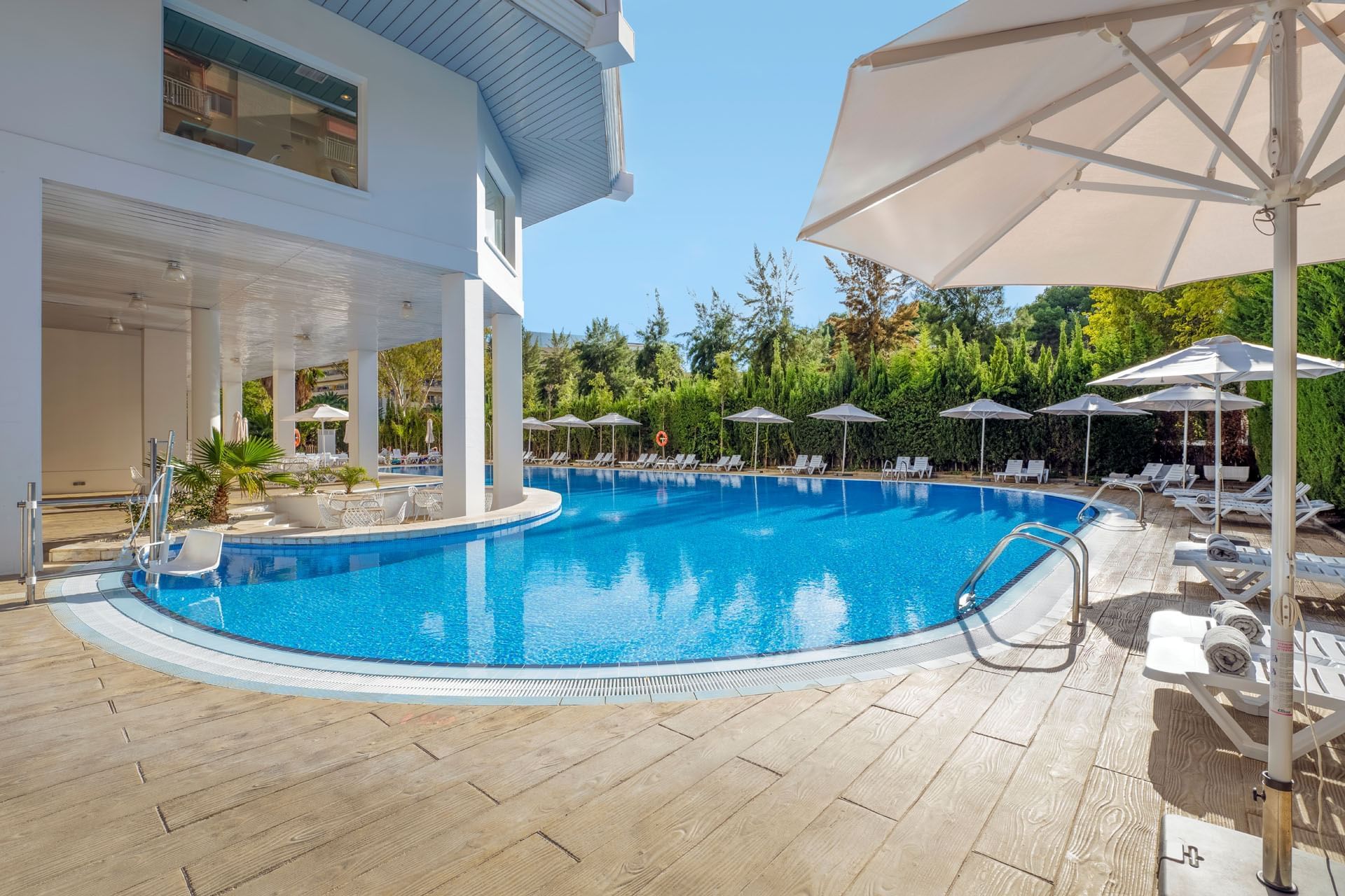 Tumbonas en la zona de la piscina al aire libre en Ponient Hotels