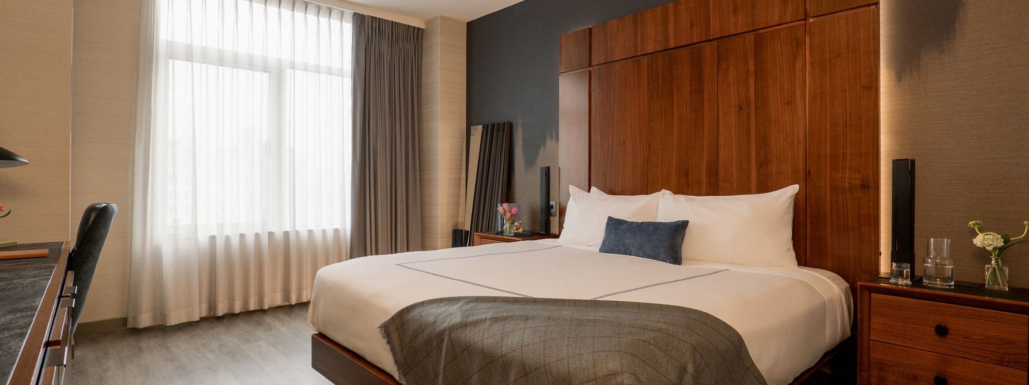 Accessible Superior Room with wooden bed, gray blanket, and white curtains at Gansevoort Meatpacking NYC, New York.